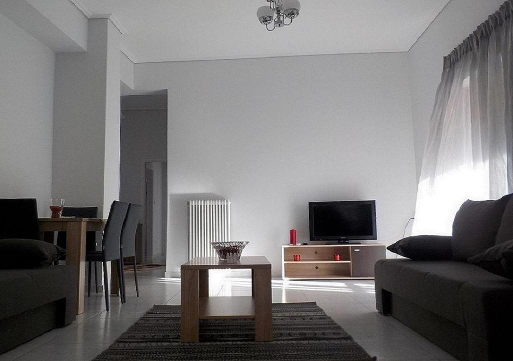 ein Wohnzimmer mit einem Sofa und einem Tisch in der Unterkunft *OI.KO HOUSE* City Apartments in Káto Achaḯa