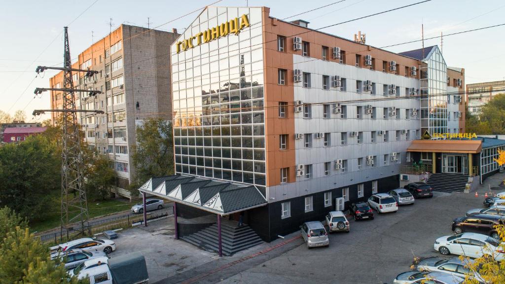 un edificio de hotel con coches aparcados en un aparcamiento en Arirang Hotel, en Khabarovsk