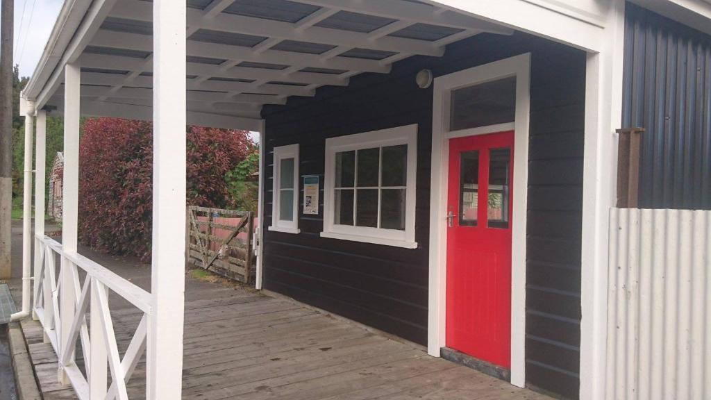 a black and red door on a house with a porch at Whanga Butcher Shop in Whangamomona