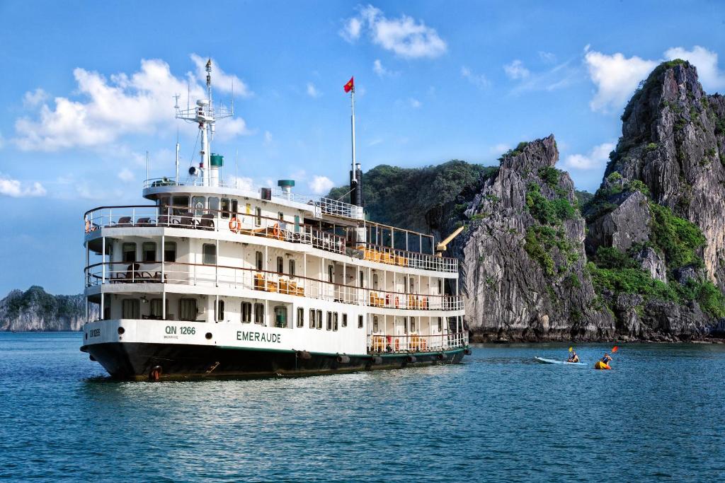 a cruise ship in the water next to a rock formation at Emeraude Classic Cruises in Ha Long