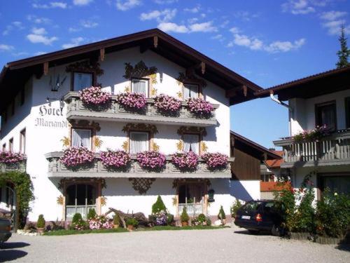 ein großes weißes Gebäude mit Blumen auf den Balkonen in der Unterkunft Hotel Mariandl in Bergen