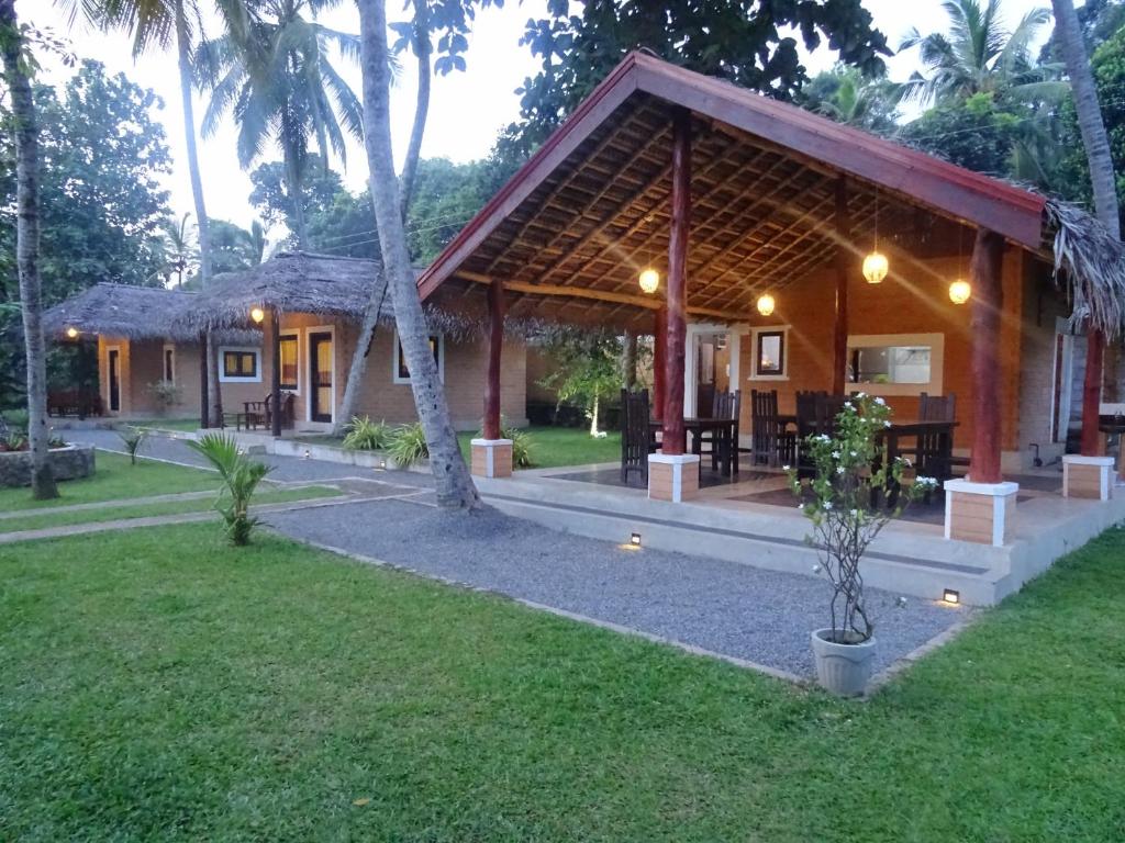 a house with a pavilion with a grass yard at airport eco cottage in Katunayaka