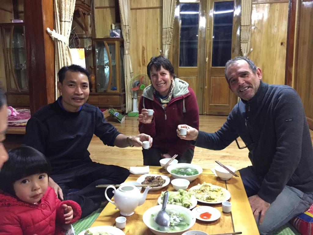 Eine Gruppe von Menschen, die an einem Tisch sitzen und Essen essen. in der Unterkunft Mu Cang Homestay in Lao San Chay