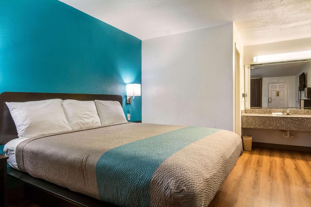 Motel 6-Freeport, TX في فريبورت: غرفة نوم بسرير كبير وجدار ازرق