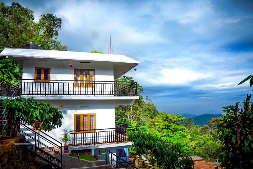 a white house on top of a mountain at Mountain Breeze Villa and Homestay in Idukki