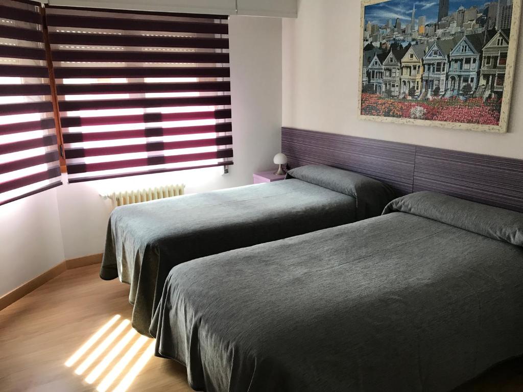 a bedroom with two beds and a window with blinds at Pension Berceo in Logroño