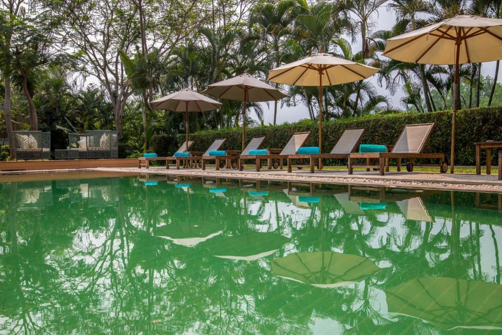 a swimming pool with chairs and umbrellas in the water at The Apsara Rive Droite in Luang Prabang