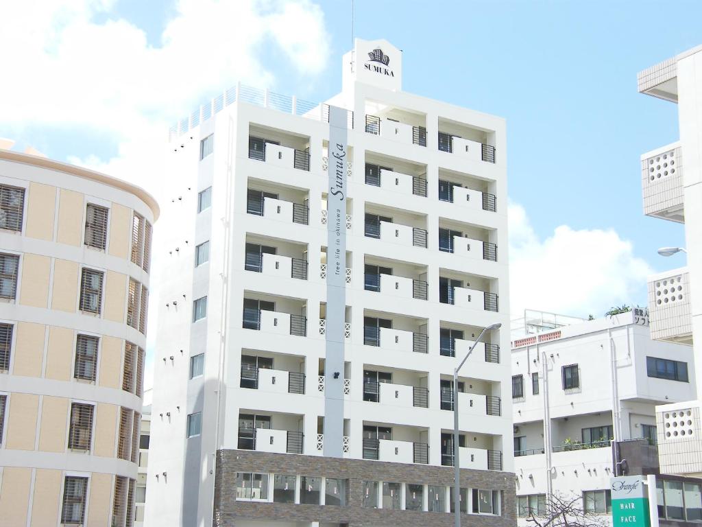 a white apartment building in the middle of buildings at Sumuka shintoshin 1LDK[901] in Naha