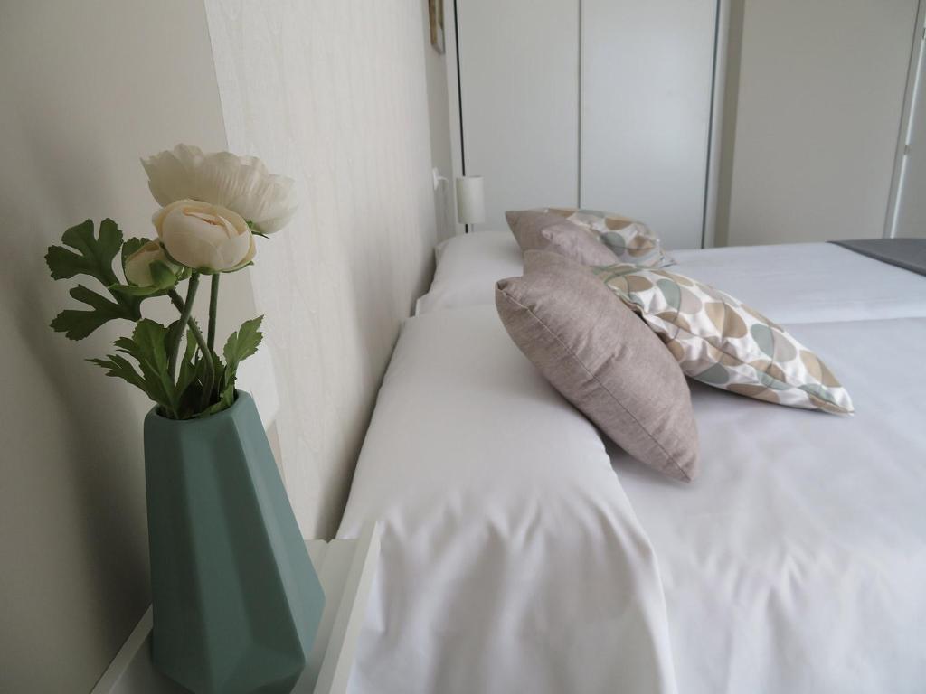 un jarrón verde con flores sentado en una cama en Alcañiz Flats II, en Alcañiz