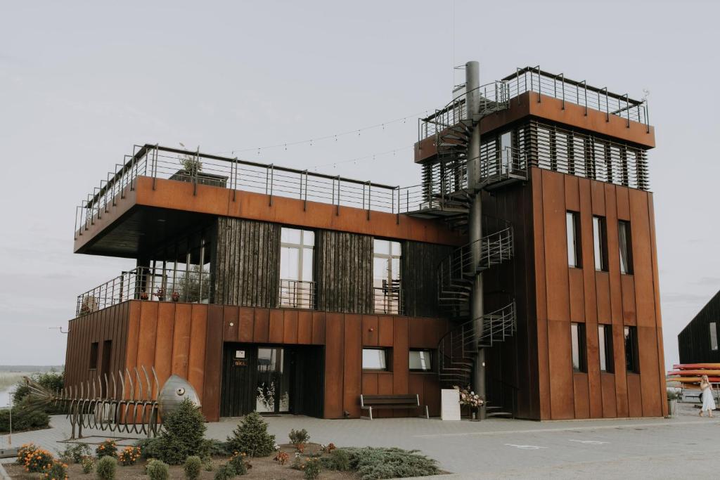 ein Gebäude mit einem Balkon und einer Treppe darauf in der Unterkunft Ūdens Tūrisma Attīstības Centrs Bāka in Gaigalava