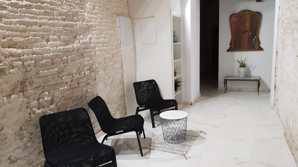 Habitación con 3 sillas, mesa y pared de ladrillo en PLAZA REDONDA brugada home, en Valencia