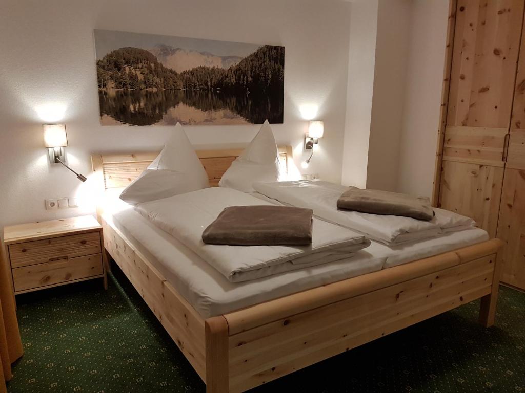 Schlafzimmer mit einem Holzbett mit weißer Bettwäsche und Kissen in der Unterkunft Haus Alpenglühn in Sautens
