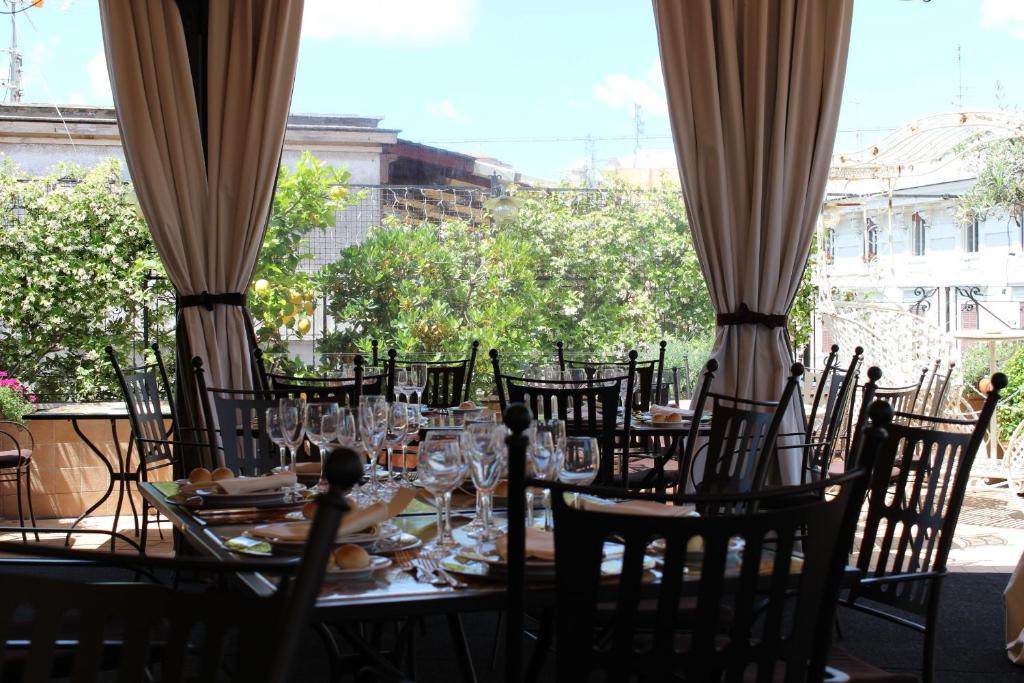 uma mesa com cadeiras e copos de vinho num pátio em Hotel dei Consoli Vaticano em Roma