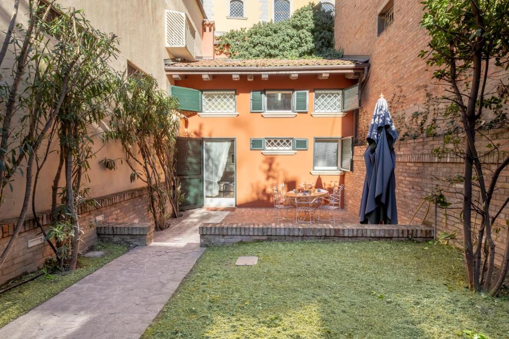 un patio de una casa con una sombrilla en el patio en Isaia Garden - BolognaRooms, en Bolonia