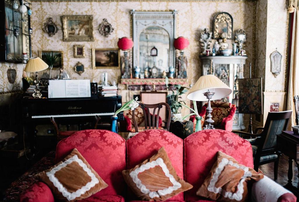 a living room with a red couch and a piano at St Benedict - Victorian Bed and Breakfast in Hastings