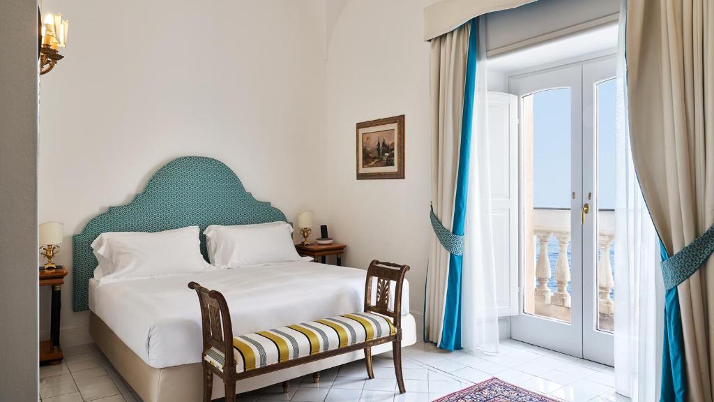 a bedroom with a large bed and a large window at Palazzo Avino in Ravello