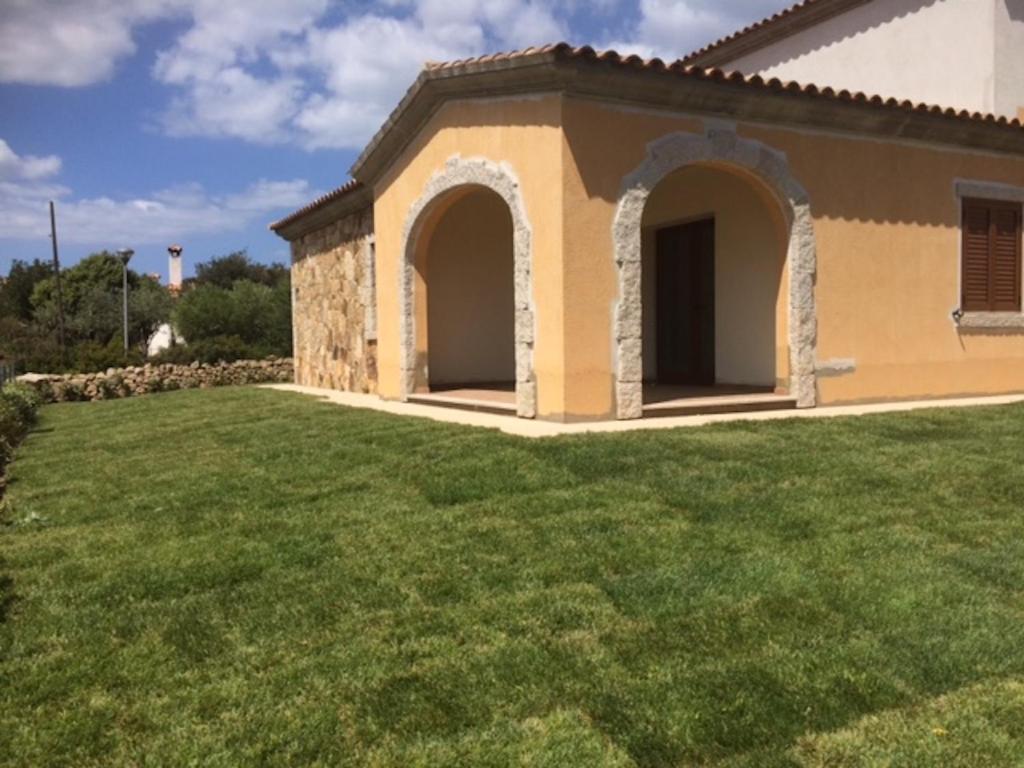 una casa con un césped verde delante de ella en Residence Arruli, en San Teodoro