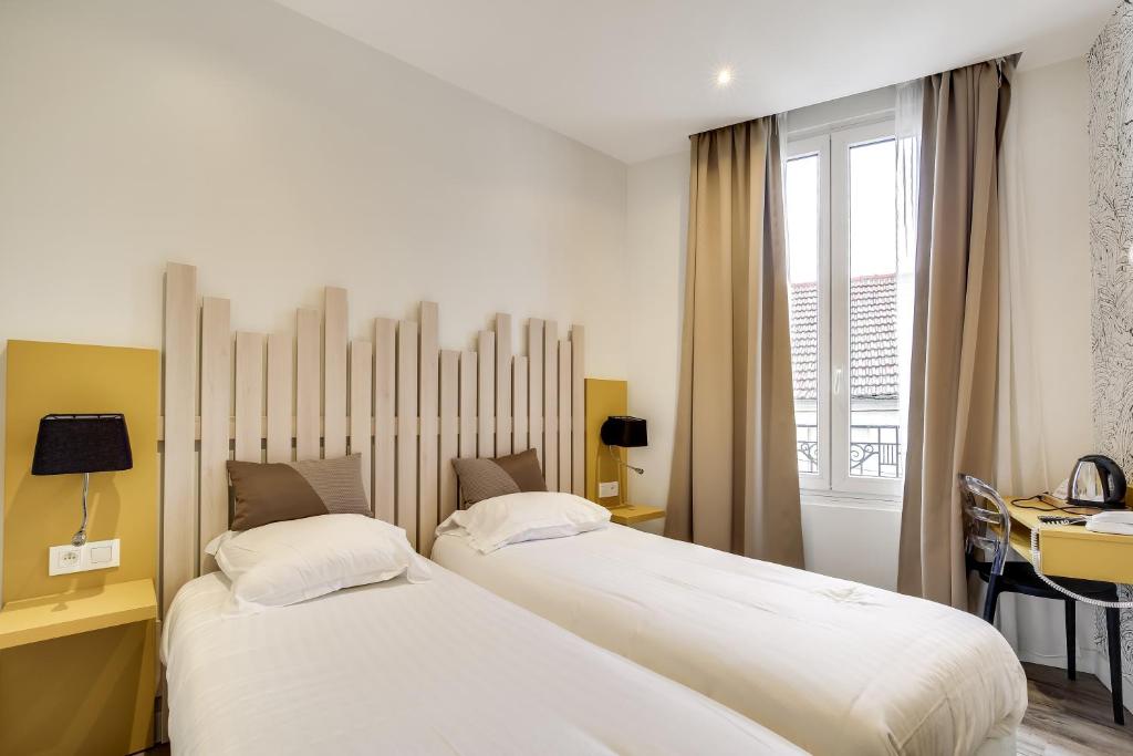 two beds in a hotel room with a desk and a desk at Hotel Des Arts in Rueil-Malmaison