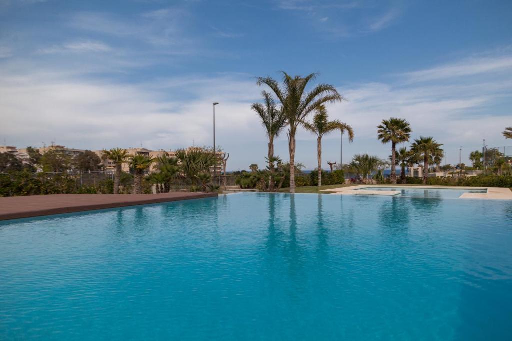een groot blauw zwembad met palmbomen op de achtergrond bij Apartment Vistamar II in Campoamor