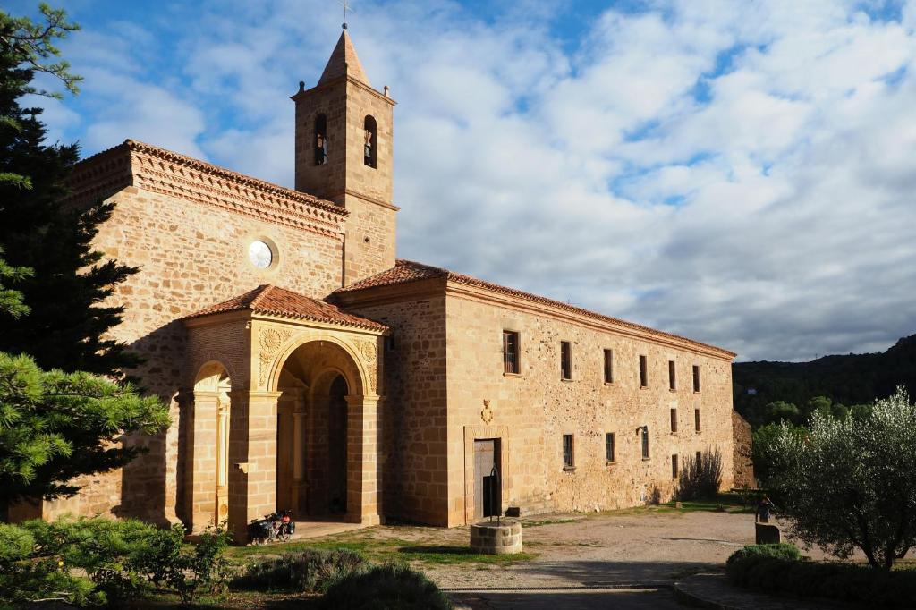 a large brick building with a clock tower on it at Monasterio El Olivar in Estercuel