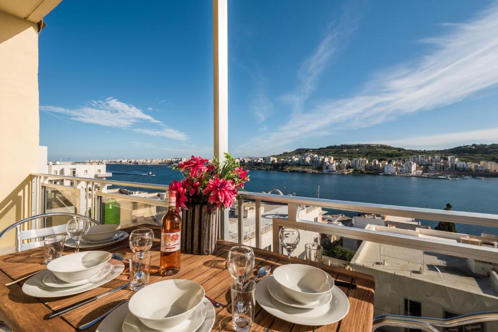 a dining table with a view of the water at Bayview 2 bedroom seaview apartment with large terrace with panoramic views - by Getawaysmalta in St Paul's Bay