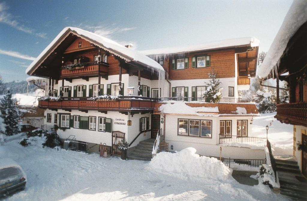 ein schneebedecktes Haus mit einem davor geparkt in der Unterkunft Landhaus Kaiserblick in Ellmau