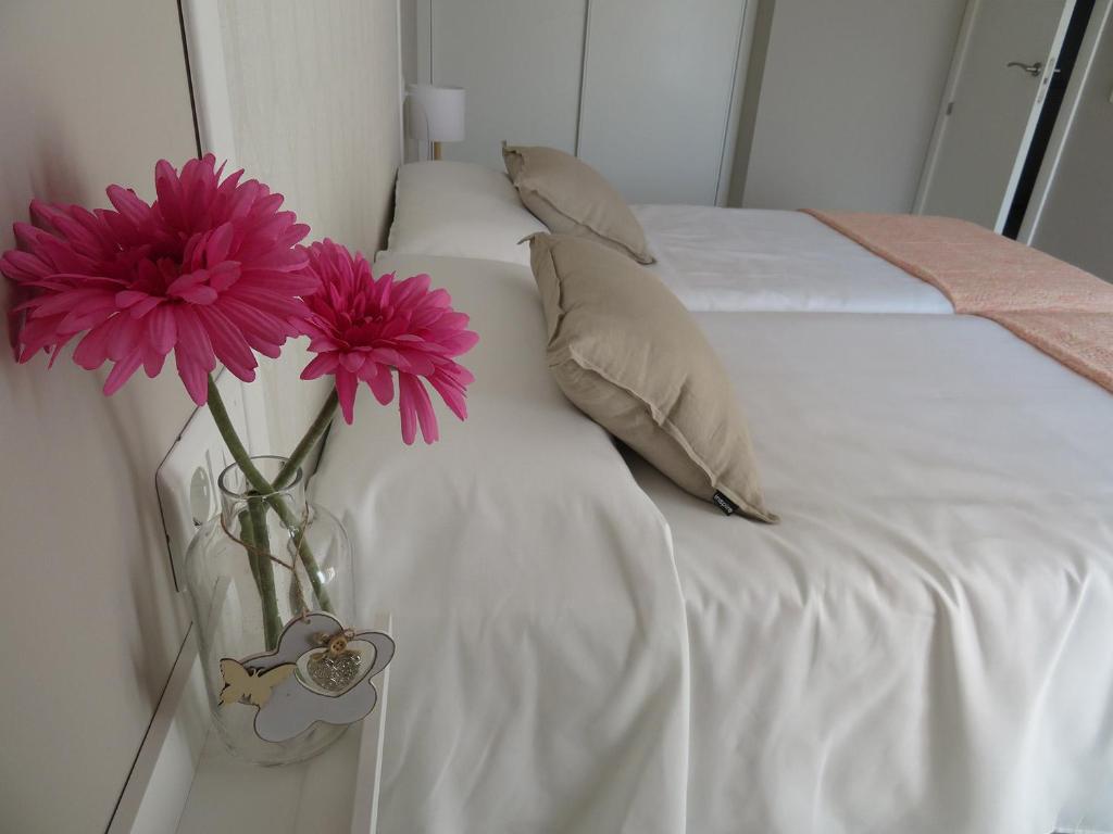 Un jarrón con flores junto a la cama en Alcañiz Flats I en Alcañiz