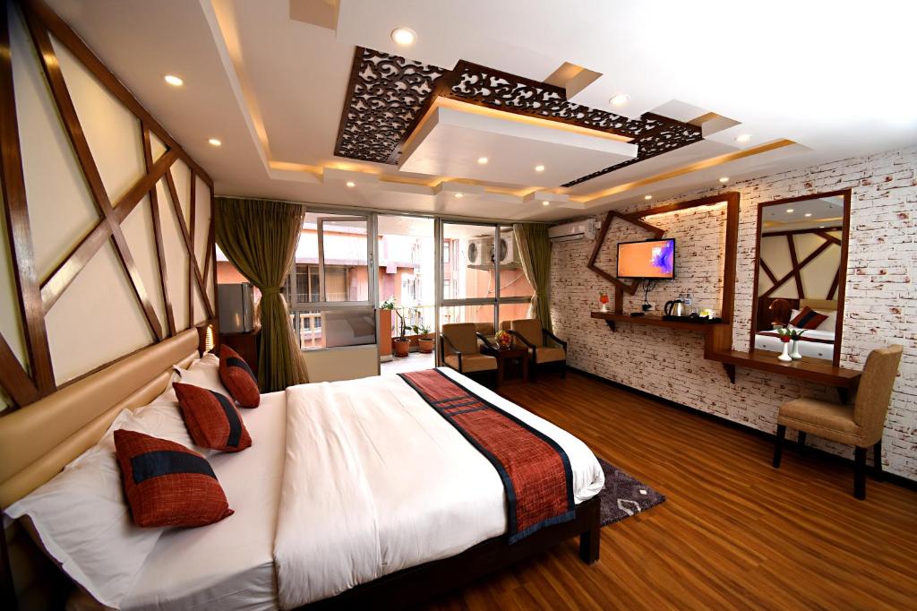 a hotel room with a bed, chair, and nightstand at Hotel Jampa in Kathmandu