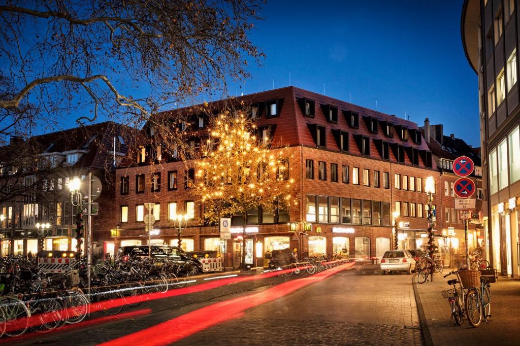 a city street at night with a christmas tree and buildings at stories by Grimm's in Münster