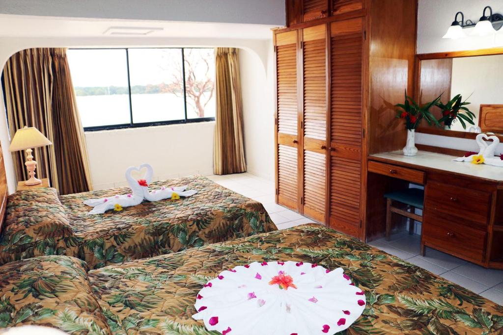 a hotel room with two beds and a desk at Crown Point Beach Hotel in Crown Point