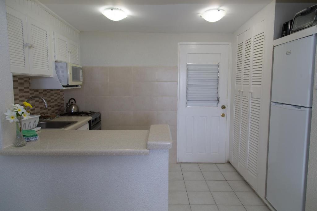 a kitchen with white cabinets and a white refrigerator at Crown Point Beach Hotel in Crown Point