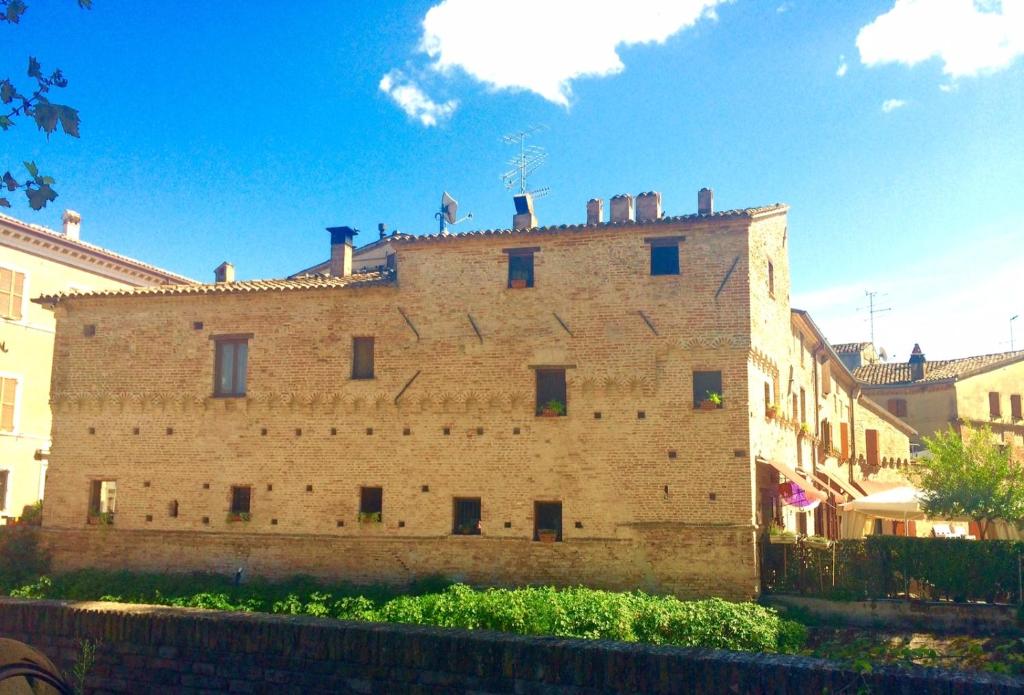 un grand bâtiment en briques avec un toit en haut dans l'établissement Locanda Delle Fate, à San Giovanni in Marignano