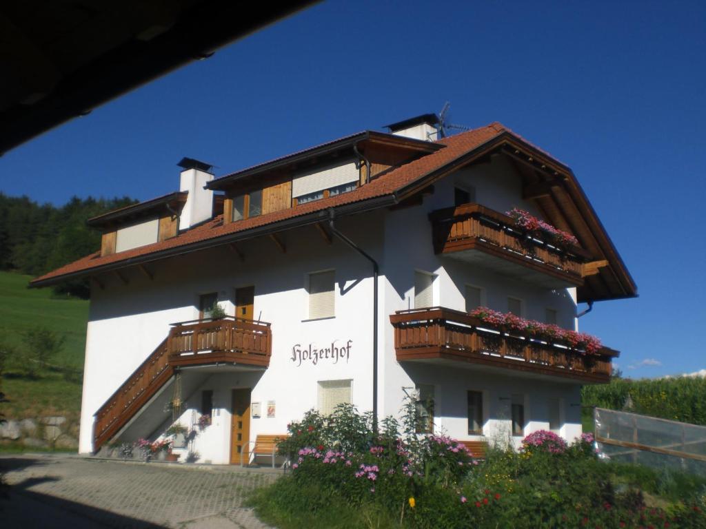 un edificio bianco con balconi e fiori di Holzerhof a San Lorenzo di Sebato