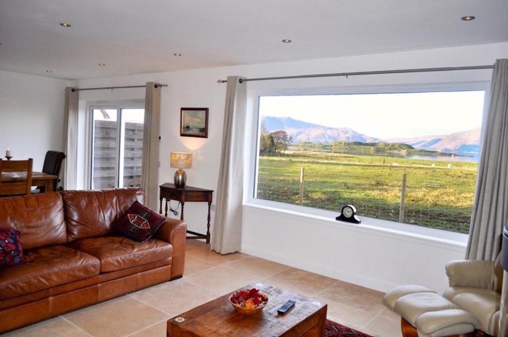 a living room with a couch and a large window at Lurach House in Port Appin