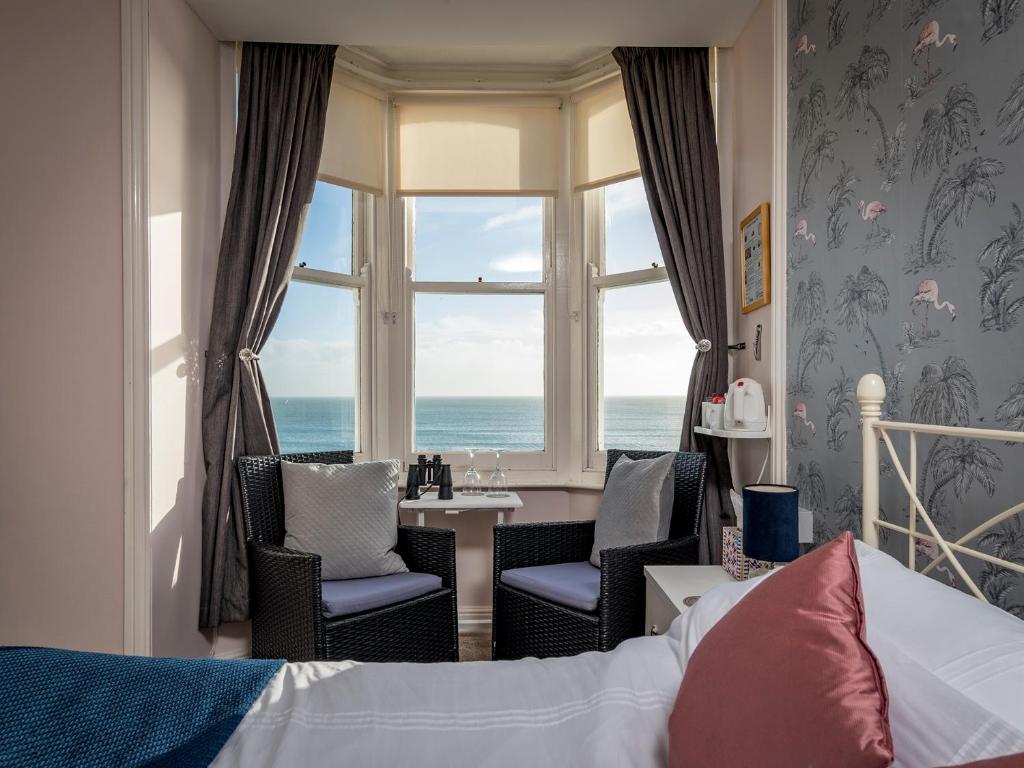 a bedroom with a bed and a table and a window at Channel View Guest House in Weymouth