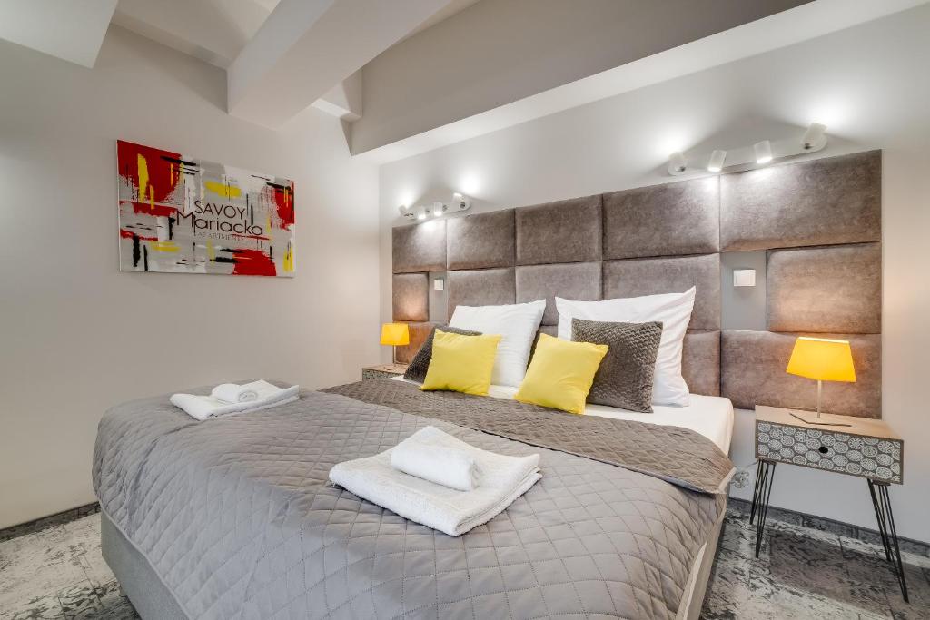 een slaapkamer met een groot bed met gele kussens bij SAVOY Mariacka Apartments in Katowice