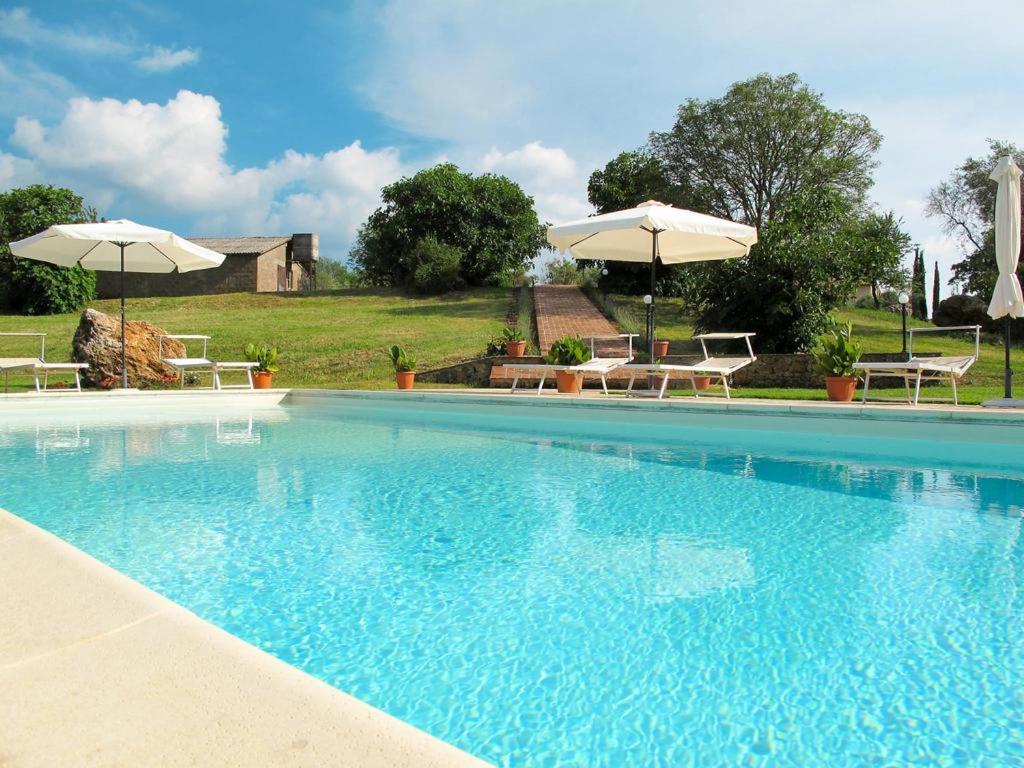 une grande piscine avec deux parasols et deux tables dans l'établissement Collepetrucci, à Ciciano