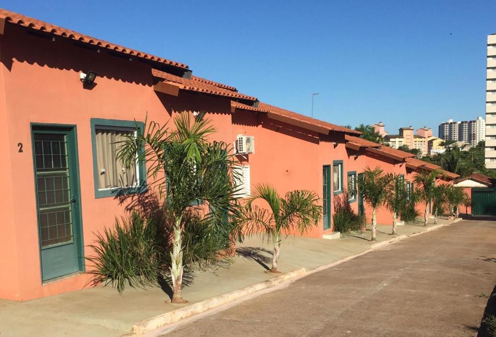 a building with palm trees in front of a street at Flat Thermas Olimpia - 300 metros do Thermas dos Laranjais in Olímpia