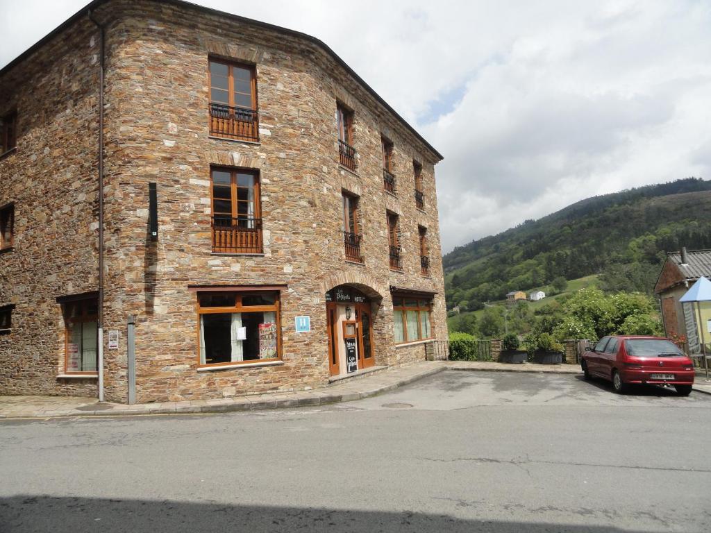 un edificio de ladrillo con un coche aparcado delante de él en Hotel Restaurante Casa Petronila, en Taramundi