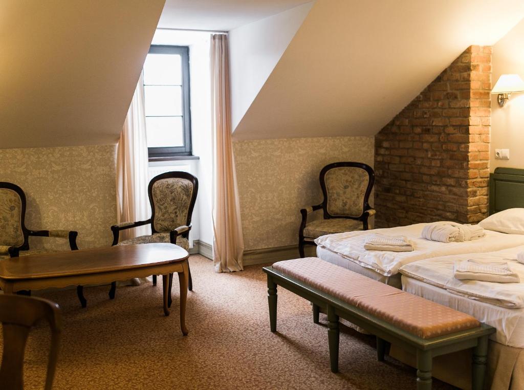 a room with two beds and a table and chairs at Hotel Usadba in Kaliningrad