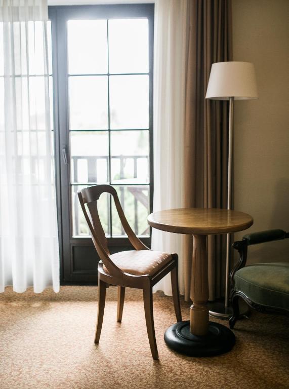 a chair and a table in a room with a window at Hotel Usadba in Kaliningrad