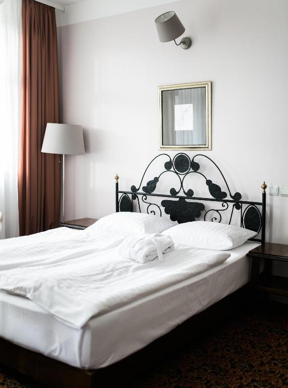 a bedroom with a large white bed with a black headboard at Hotel Usadba in Kaliningrad