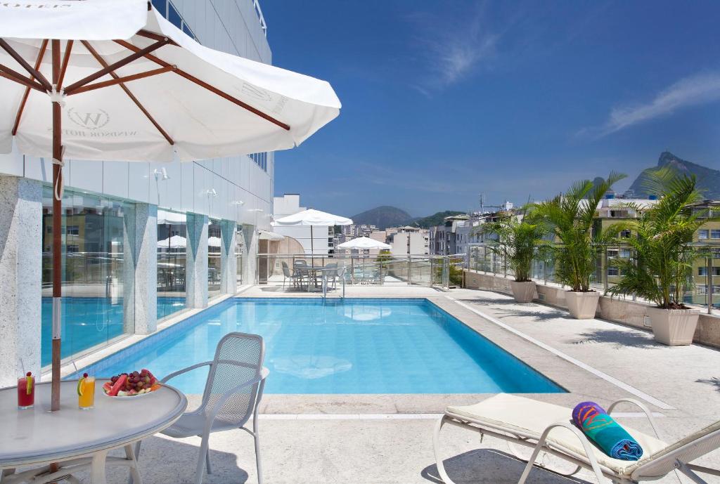 una piscina con mesa, sillas y sombrilla en Windsor Florida Hotel en Río de Janeiro