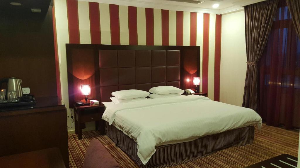 a large bed in a hotel room with two lamps at Elaf Suites Al-Andalus in Jeddah