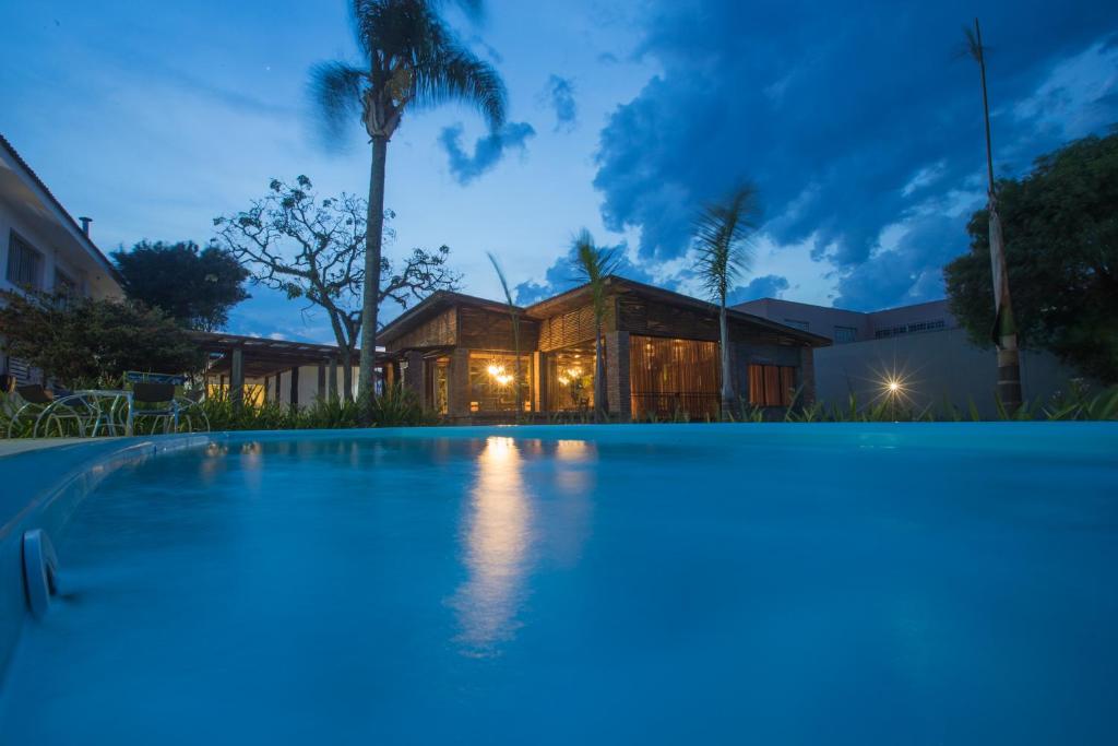 una piscina frente a una casa por la noche en Ipê Hotel Express, en Ponta Grossa