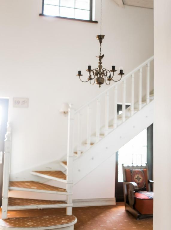 a white staircase in a living room with a chandelier at Hotel Usadba in Kaliningrad