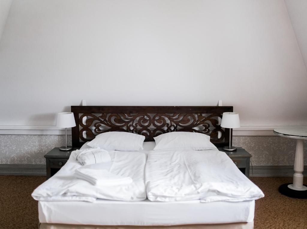 a white bed with white sheets and pillows at Hotel Usadba in Kaliningrad