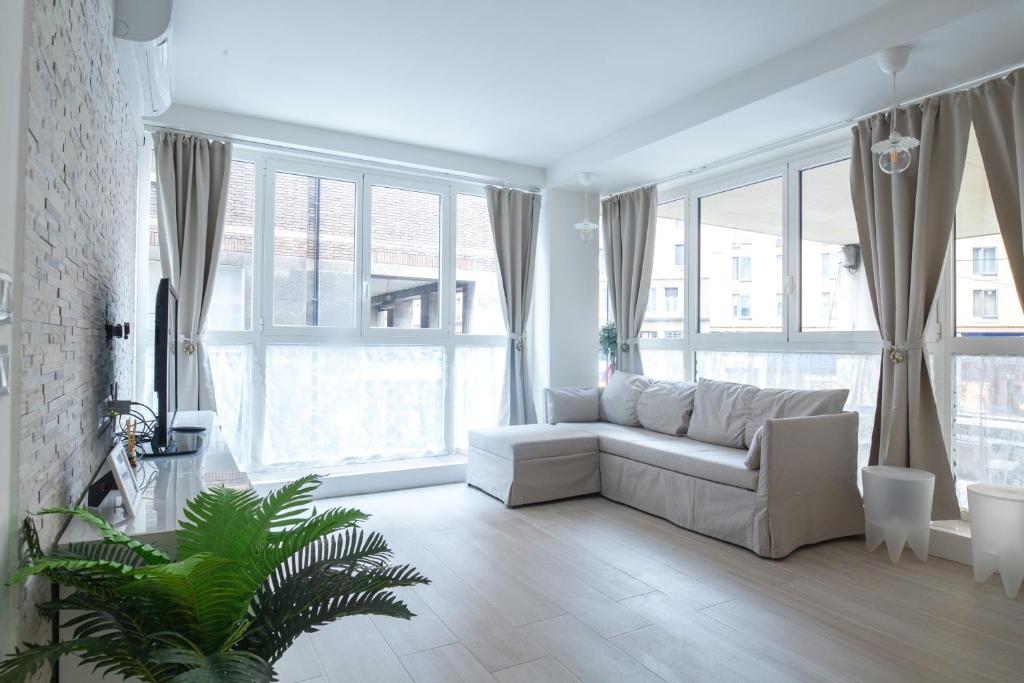 - un salon avec un canapé blanc et de grandes fenêtres dans l'établissement Marconi Apartments, à Bologne