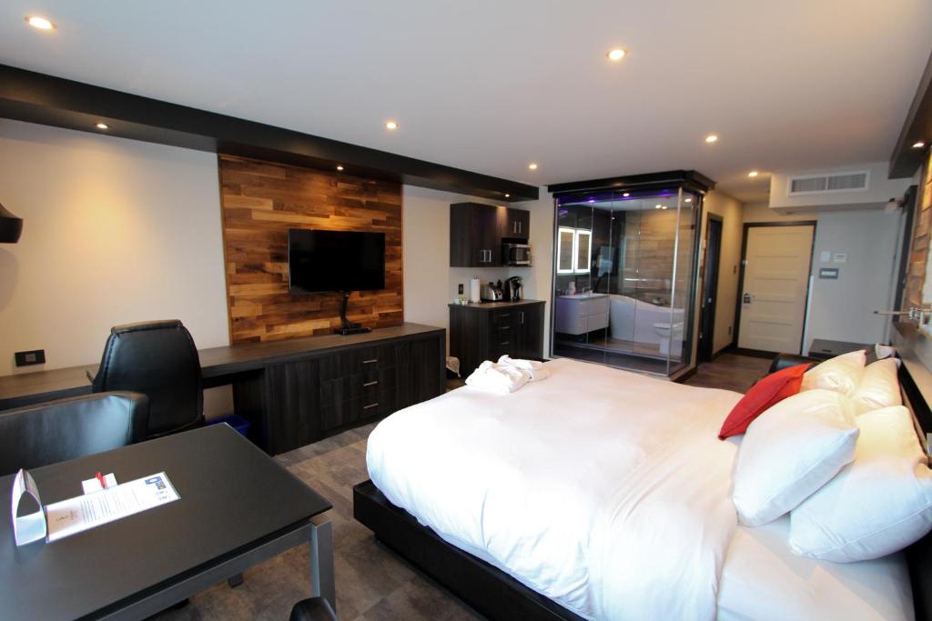 Dormitorio con cama, escritorio y TV en Hôtel Saint-Germain Rimouski en Rimouski
