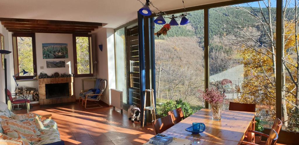 uma sala de estar com uma mesa e janelas grandes em Ca l'ESTRELLA em Queralbs